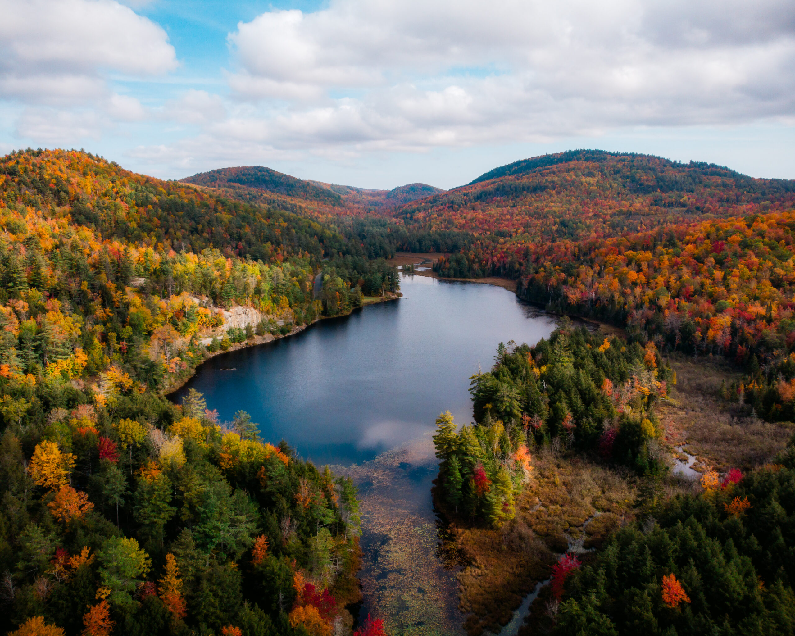 A photograph of a pond in the Adirondacks surrounded by brilliant fall foliage.